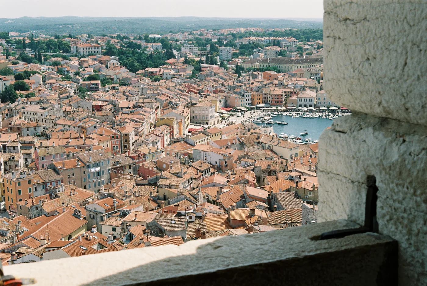 Town rooftops and water seen from a high stone window