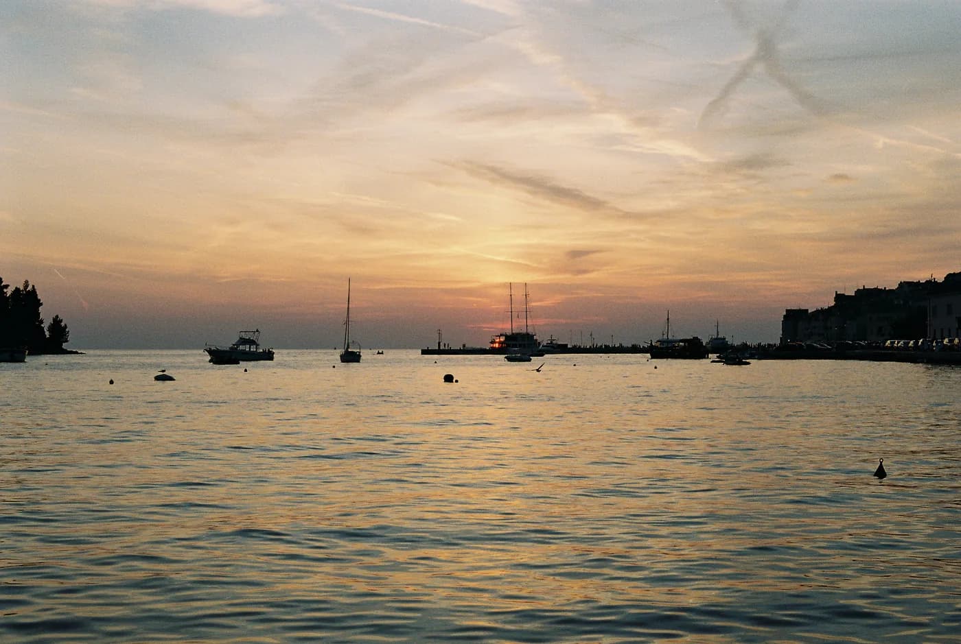 Boats on calm water beneath a warm evening sky