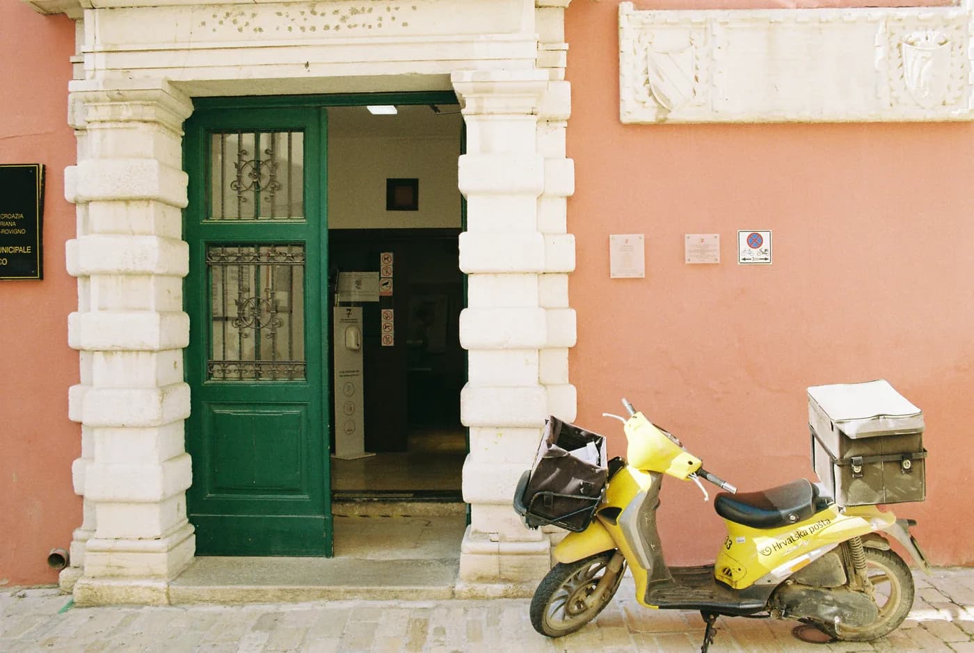 Yellow moped parked outside a green doorway