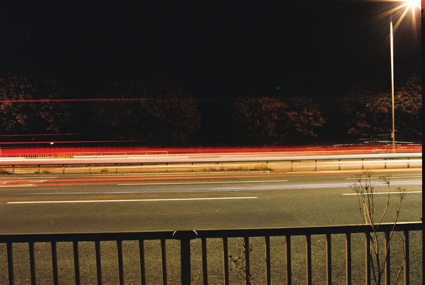 Red and white light trails along a road at night
